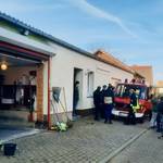 Ansicht eines Gerätehauses mit FFW-Kameraden und FFW-Fahrzeug