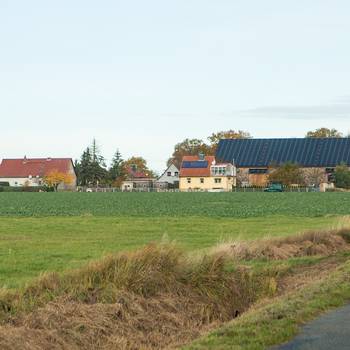 rechts im Vordergrund die Straße nach Ottersburg, im Hintergrund der Ort mit einem großen Gebäude mit PV-Anlage