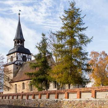 Kirche in Uchtdorf mit Friedhofsmauer im Vordergrund
