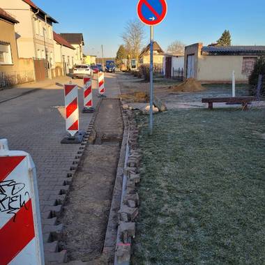 aufgenommenes Straßenpflaster und Warnbaken bei der Reparatur der Regenentwässerung in Birkholz