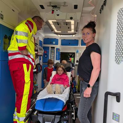Die Kinder lassen sich von einem Rettungssanitäter die Technik erklären und probieren die Trage aus