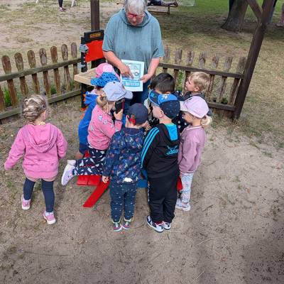 Eine Erzieherin erklärt einer Gruppe Kindern die Notrufnummer 112.