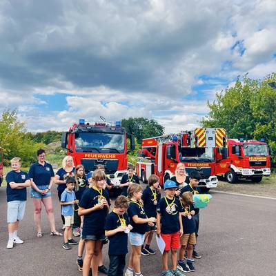 Die Kinder stehen vor den Feuerwehrahrzeugen und sind stolz auf Ihre erhaltenen Medaillen.