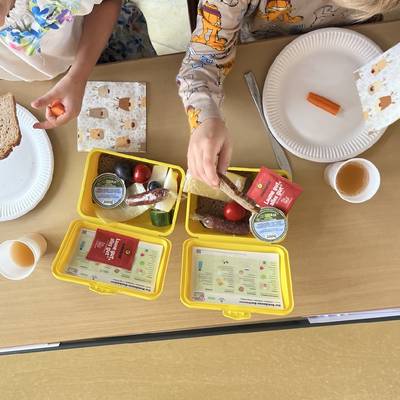 Die Kinder der ersten Klasse packen Ihre Frühstücksboxen aus und trinken frischen Apfelsaft