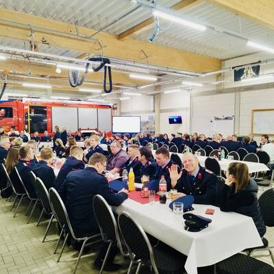 Die Kammeraden der Feuerwehren Lüderitz und Groß Schwarzlosen sitzen an langen Tischen bei der Jahreshauptversammlung