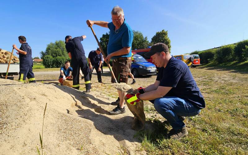 die Wasserwehr befüllt Sandsäcke ©Einheitsgemeinde Stadt Tangerhütte vorn links ein Berg mit Sand; dahinter die Teilnehmer der Wasserwehrschulung, welche Sandsäcke befüllen